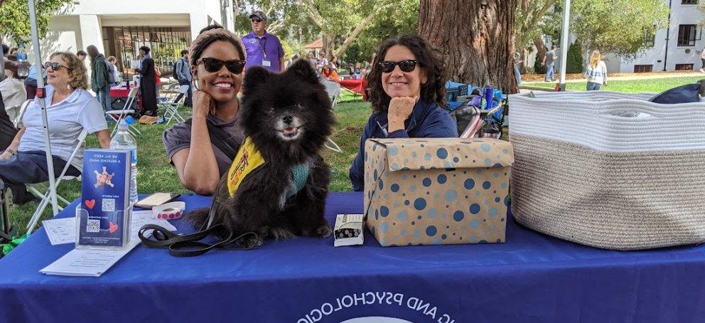 Two CAPS therapists with Joey the therapy dog out on the Quad 